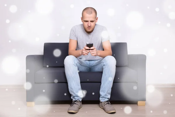 Junger Schöner Mann Sitzt Mit Smartphone Auf Sofa — Stockfoto