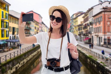 Genç ve güzel bir kadın turistin portresi. Eski İtalyan kasabasında akıllı telefonuyla selfie çekiyor.