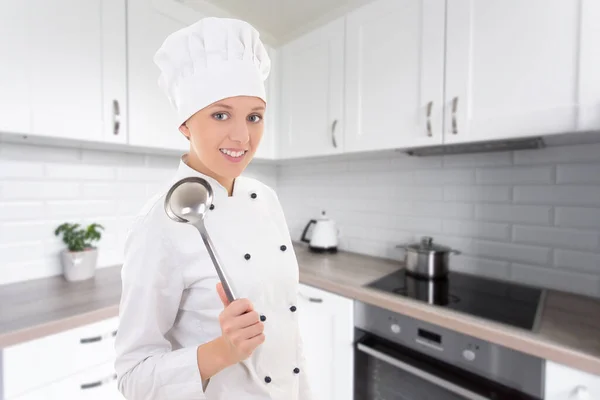 年轻快乐的女人穿着厨师制服 在现代厨房里拿着大铁勺 — 图库照片