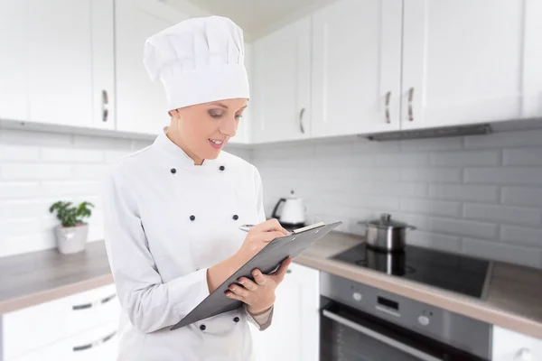 Retrato Jovem Mulher Uniforme Chef Escrevendo Algo Área Transferência Cozinha — Fotografia de Stock