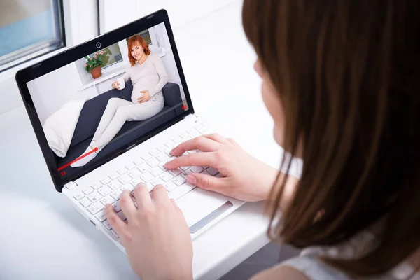 ビデオブログのコンセプト 妊娠に関するラップトップのビデオを見ている女性のバックビュー — ストック写真