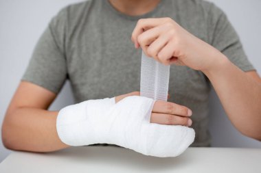 Kırık ve ilk yardım konsepti - elini bandajlayan adam