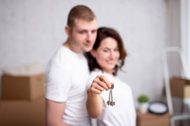 Taşınma günü. Yeni evlerinin ya da dairelerinin anahtarlarını tutan genç bir çift. tuşlara odaklan