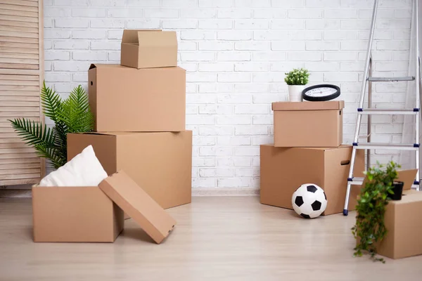 搬家日的概念 在新的房子或公寓里堆放在白色砖墙背景上的移动盒子 — 图库照片