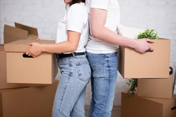 moving day concept - close up of couple holding cardboard boxes ready to moving day