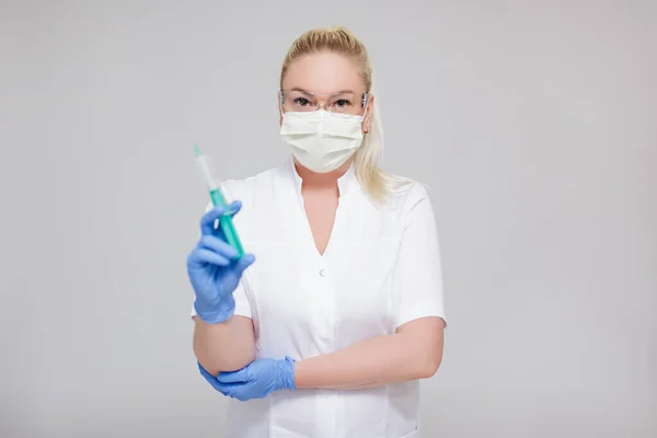 保健和疫苗接种概念 身穿白衣 头戴口罩 头戴灰色背景注射器的女医生或护士 — 图库照片