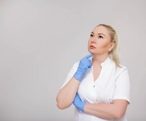 Retrato Bela Loira Médica Enfermeira Cosmetologista Uniforme Branco Pensando Algo — Fotografia de Stock