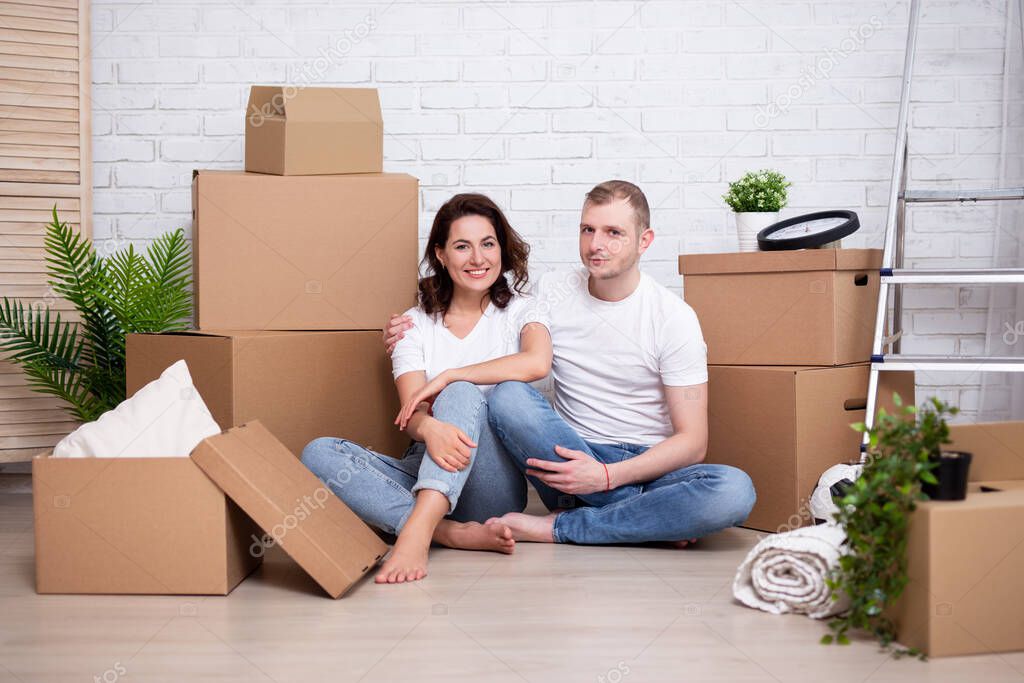 moving day concept - young couple resting after moving in new house or flat