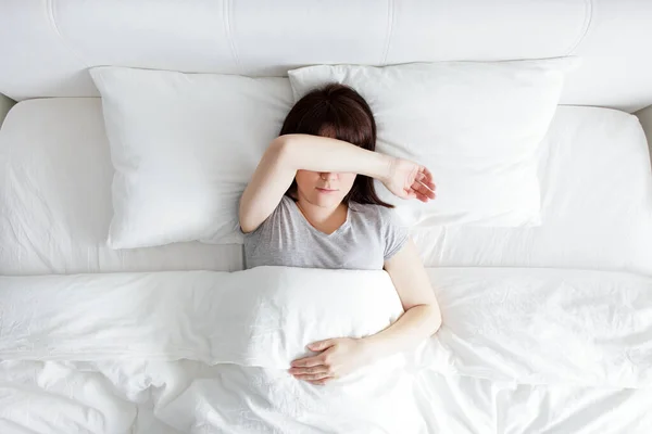 ストレスと不眠の概念 ベッドに横たわって手で顔を覆う若い女性のトップビュー — ストック写真