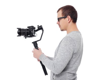 Beyaz arkaplanda izole edilmiş gimbal dengeleyicisi üzerinde dslr kamera kullanan profesyonel videografın yan görünümü