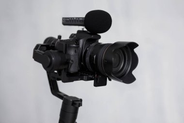 Video konsepti - Gri arkaplan üzerinde mikrofon bulunan 3 eksenli titreşim sabitleyicili modern dslr kamerayı kapat