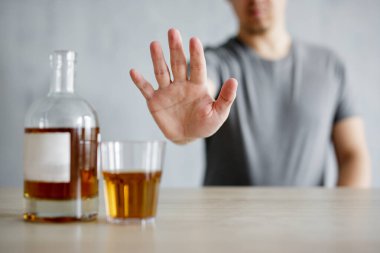 Alkolizm konsepti - genç adam açık el hareketleriyle viski bardağını reddediyor