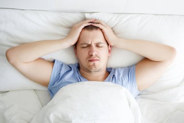 uykusuzluk, depresyon ya da baş ağrısı konsepti - yatakta yatan stresli genç adamın üst görünümü