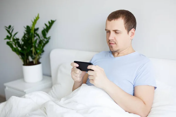 Retrato Feliz Jovem Bonito Homem Sentado Cama Sob Cobertor Assistir — Fotografia de Stock