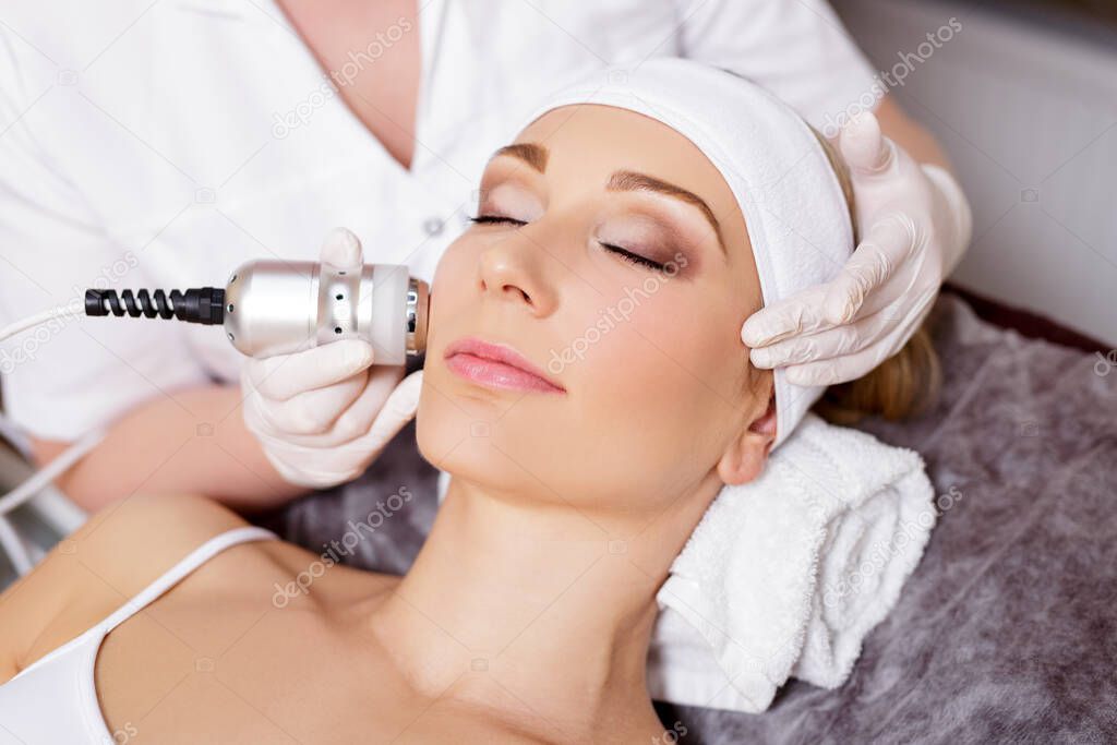 cosmetology and beauty concept - beautiful woman getting facial treatment or anti-aging procedure in beauty salon