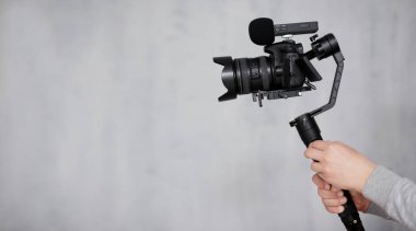 modern dslr kamera 3 eksenli dengeleyici üzerinde takip eden odak sistemi erkek videograf Gri arkaplan üzerinde kopyalama alanı ile