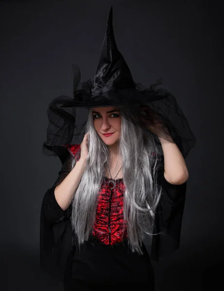 ハロウィンのコンセプト 黒魔女ハロウィンの衣装を着た謎の女性の肖像と黒の背景の上にポーズ帽子 — ストック写真