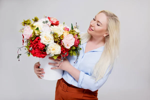 美しいとエレガントなプラスサイズブロンド女性保持ボックスで夏の花以上グレーの背景 — ストック写真