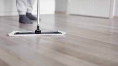 Oda servisi konsepti. Oturma odasında ahşap yerleri paspaslayan adam.