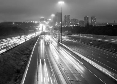 Highway 401 Toronto siyah beyaz çiseleyen yağmur yağmur üzerinde iz ışıkları ve yüksek binaların görünümünü