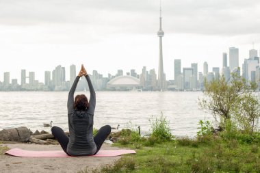 Orta yaşlı kadın yoga lotus pozisyonu Toronto Adası üzerinden ön Ontario Gölü üzerinde pratik