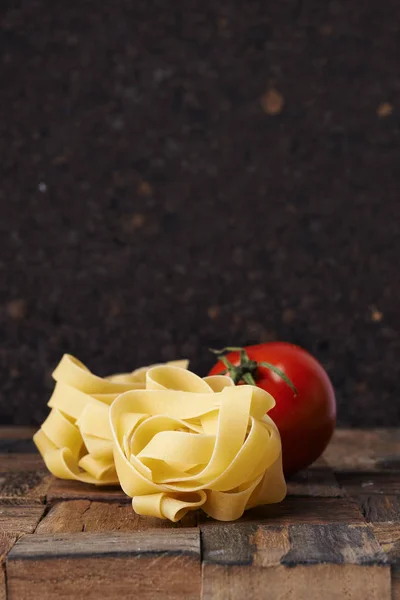 Raw fettuccini and fresh tomatoes — Stock Photo, Image