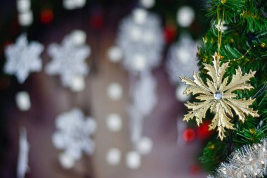 Altın Noel kar tanecikleri - yeşil bir Noel ağacına asılı beyaz kar tanelerinin arka planına