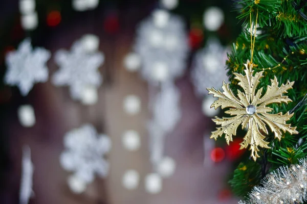 Altın Noel kar tanecikleri - yeşil bir Noel ağacına asılı beyaz kar tanelerinin arka planına