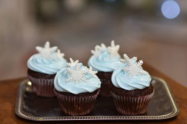 Muffinki na tacy na stole z białym kremem białkowym z płatkami śniegu — Zdjęcie stockowe