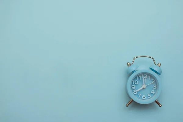 Relógio azul despertador sobre um fundo azul claro, lugar para uma inscrição — Fotografia de Stock