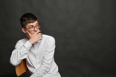 Ağzını eliyle kapatan bir adam, bilinçaltı hareketi sıklıkla tereddüt, şok, gizlilik ya da vücut dilindeki iç anlaşmazlıkla ilişkilidir. Gözlüklü adam eli ağzında oturuyor..