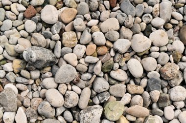 Yuvarlak sahil taşlarının ve çakıl taşlarının üzerine yumuşak bir ışık. Çakıl taşları renk çeşitliliği ve desen sunar. Sahilde çeşitli çakıl taşları karışımı dokunulabilir, görsel ilgi.... 