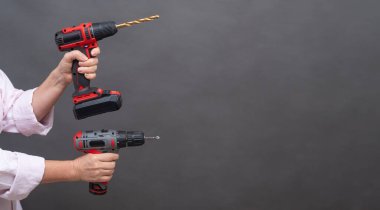 İki kablosuz matkap, matkap uçları genişletilmiş kırmızı ve siyah aletler, izole arka plan, onarım ve DIY projeleri. Ellerde gösterilen kablosuz matkaplar, modern elektrikli aletler. Boşluğu kopyala 