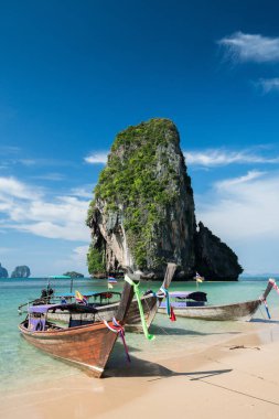 Güzel Ao Nang Beach mavi gökyüzü ve masmavi deniz ve kalker kayalar, Phi Phi Islands, Tayland bir arka plan üzerinde renkli uzun kuyruk tekneler 