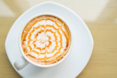 Sıcak macchiato kahve karamel tarafından ahşap masa üzerinde beyaz Kupası ile