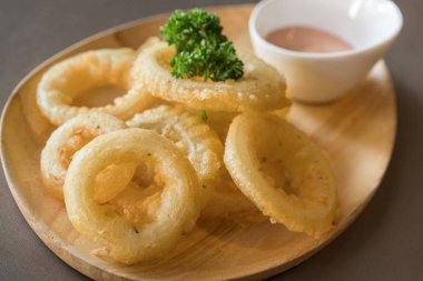 meyilli ahşap masa üzerinde soslu kızarmış soğan halkaları