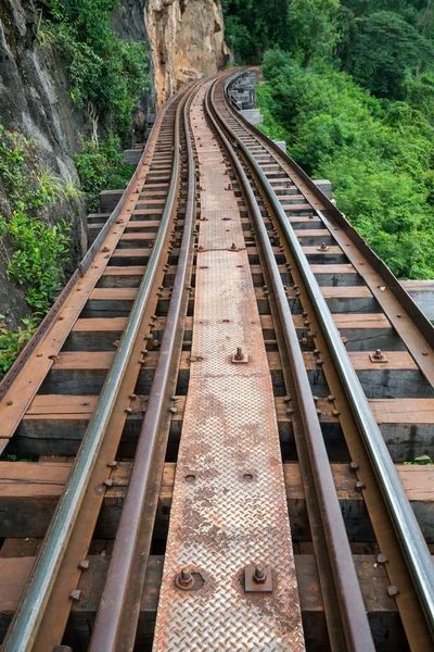 Old railroad tracks on bridge beside cliff rock — Stock Photo, Image