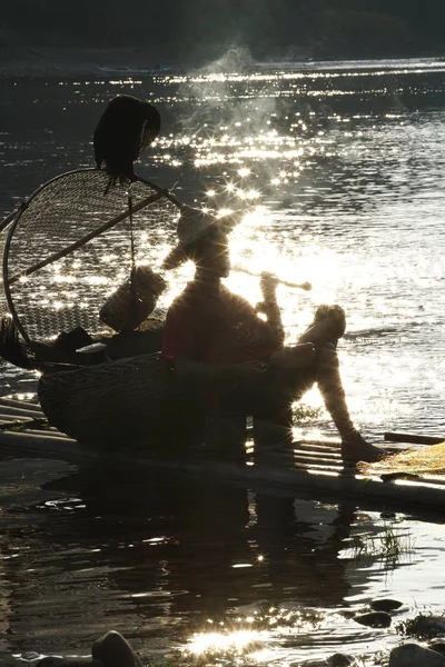 Silhouet van de visser van de aalscholver op de oude bamboe boot wit — Stockfoto