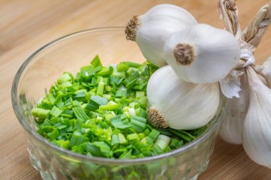 Pişirme için önceden kesilmiş kesme tahtası üzerinde doğranmış yeşil sarımsak. 