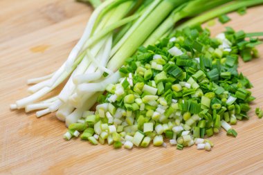Pişirme için önceden kesilmiş kesme tahtası üzerinde doğranmış yeşil sarımsak. 