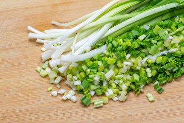 Pişirme için önceden kesilmiş kesme tahtası üzerinde doğranmış yeşil sarımsak.