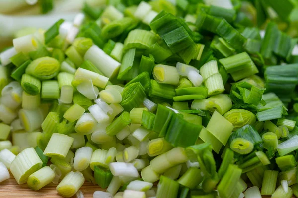 Нарезанный зеленый чеснок на разделочной доске, приготовленный для приготовления пищи . Стоковое Фото