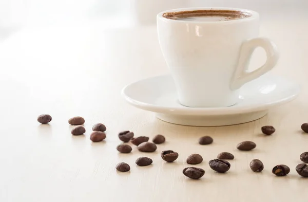 Ontbijt. Kopje koffie en koffiebonen op witte tafel — Stockfoto