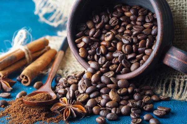 Granos de café derramados de una taza de barro y esparcidos en un azul —  Fotos de Stock