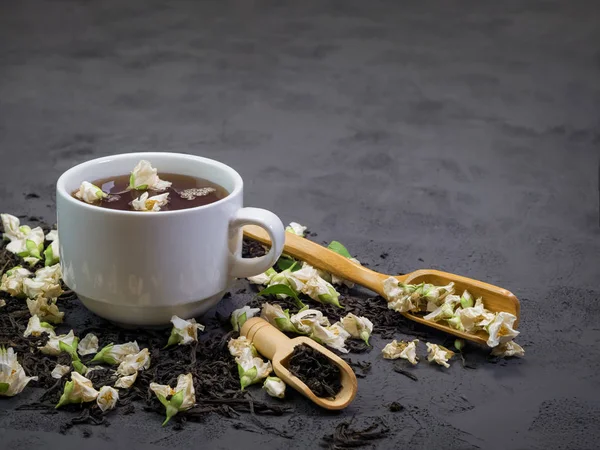 Schwarzer Tee in einer weißen Tasse auf texturiertem Hintergrund, mit trockenem Tee — Stockfoto