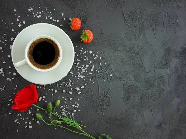 Kop med kaffe på et teksturbord med valmueblomst - Stock-foto