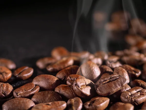 Kaffeekörner schließen sich vor schwarzem, glänzenden Hintergrund. Makro. Lebensmittelkonsum — Stockfoto