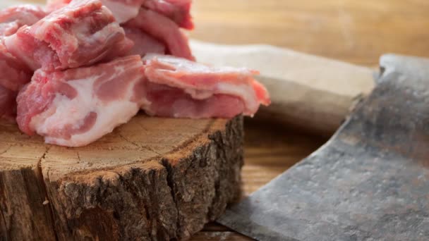Siekiera i kawałki posiekanego mięsa leżą na drewnianym stole na drewnianej desce. Przejście kamery wideo wzdłuż stołu — Wideo stockowe