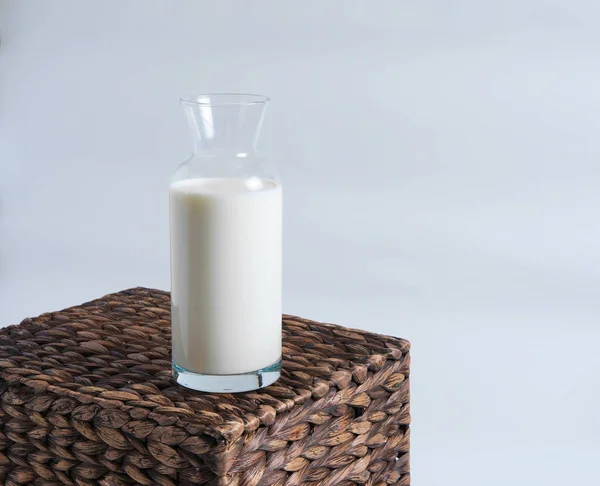 Milk in a glass bottle stands on a wicker box