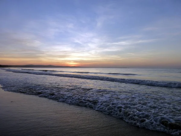 Prachtige zonsondergang. de zon in de zee. Zand strand en blauwe hemel met wolken. — Stockfoto